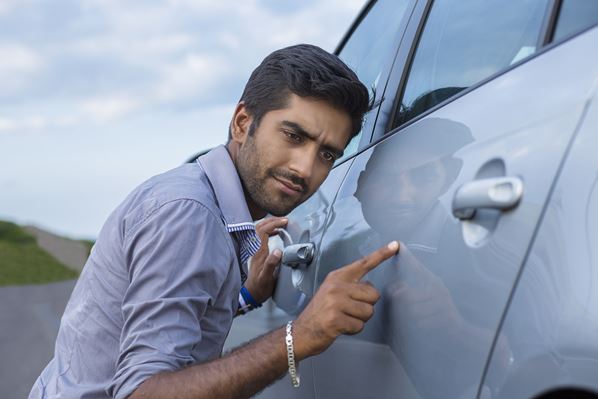 Car repair shop manager inspecting vehicle