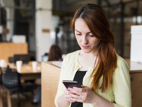 Customer in a café ordering coffee on her mobile phone