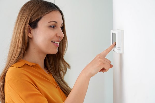Women adjusting a heating thermostat