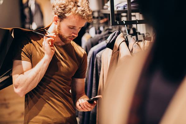 Customer in a clothes shop looking at his phone