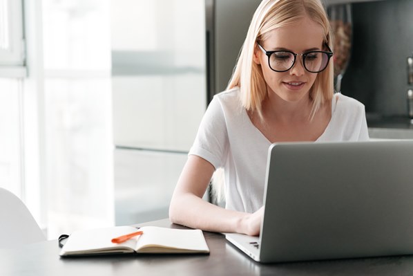 Student writing on her laptop at home