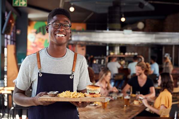Happy waiter helping customers